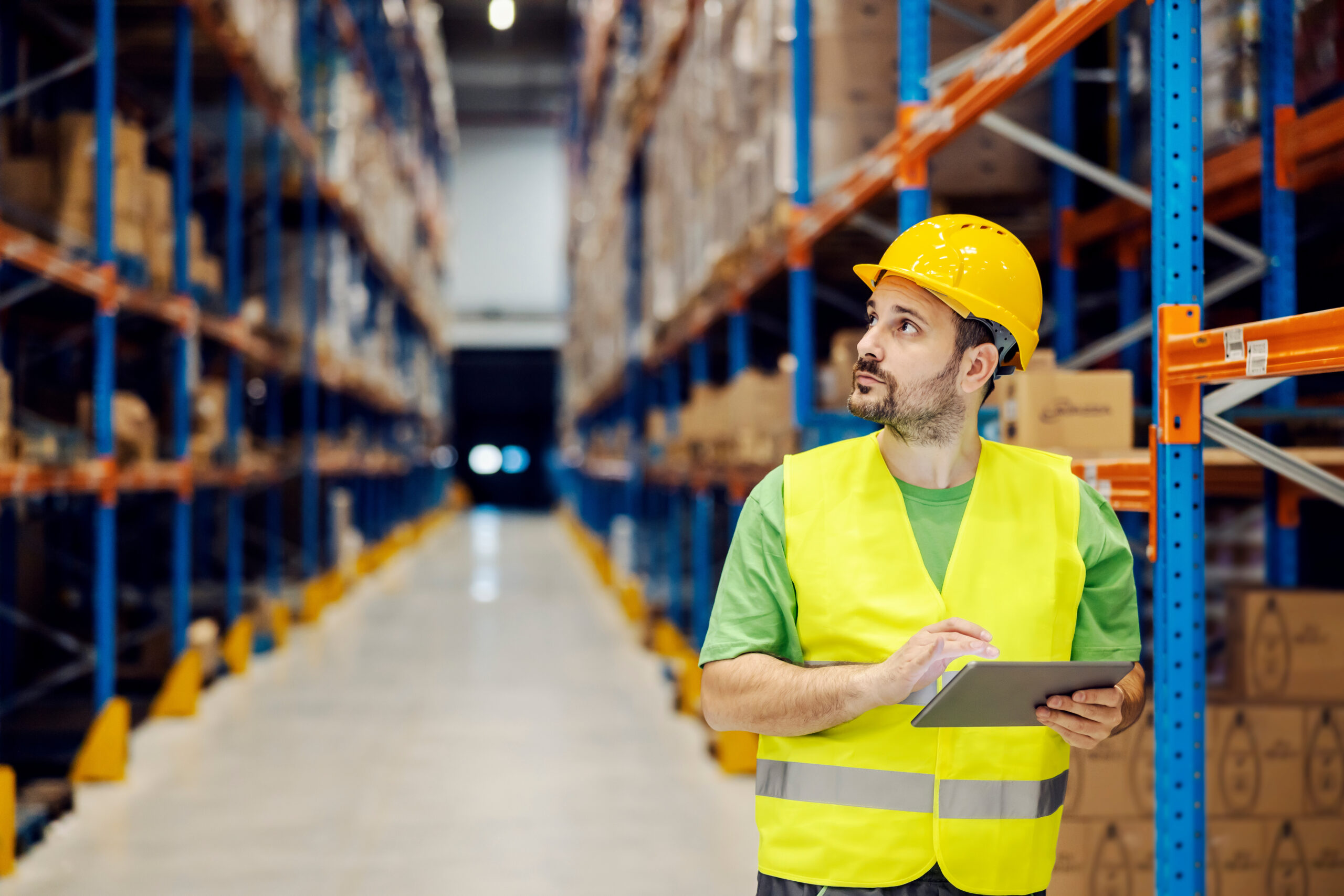 Home a storage worker scrolling on tablet and looking at shelf with goods.