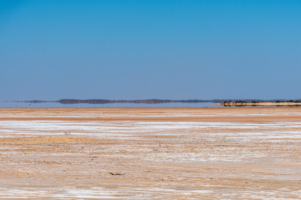 Desert mirage shimmering over a dry salt flat — a convincing illusion of water on the horizon that doesn't exist, like generic AI producing confident but fabricated MRO data classifications